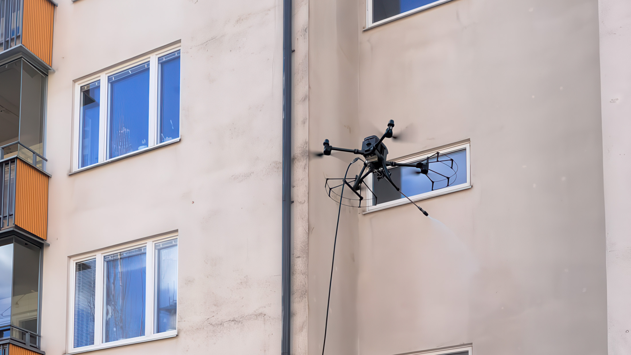Fasadtvätt med drönare som svävar en bit från fasaden och sprutar vatten.