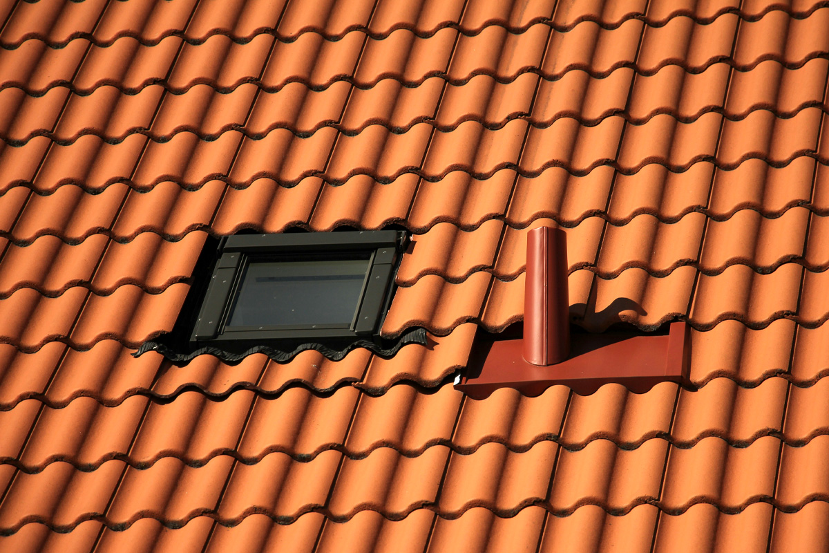 Rengjorda taktegel på ett hustak. I bild syns också ett takfönster och ventilationsrör.